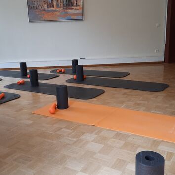 Raum vorbereitet mit Matten und Faszienrollen für einen Kurs