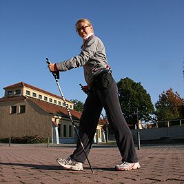 Frau mit Nordic Walking Stöcken kurz vor Kursbeginn